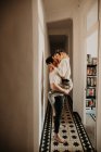 Passionate man and woman embracing and kissing at wall in hall at home — Stock Photo