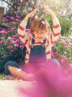 Симпатичний молодий хлопчик сидить з закритими очима і кидає гальку в сад — стокове фото
