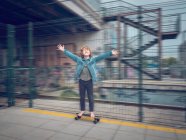 Drôle pieds nus garçon sur skateboard avec levant mains sur train plate-forme — Photo de stock