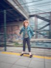 Смішний босоніж хлопчик на скейтборді на залізничній платформі — стокове фото