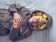 Tranquilo bonito menino na grinalda de flores amarelas deitado na cama — Fotografia de Stock