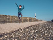 Fröhlicher Junge springt am Leuchtturm — Stockfoto