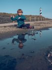 Boy at beacon reflecting in puddle — Stock Photo