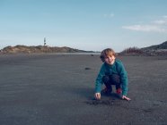 Веселый мальчик играет с песком — стоковое фото