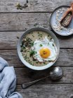 Bowl of yummy grain porridge with fried egg on wooden tablet — Stock Photo