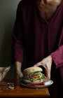 Крупним планом жінка насолоджується вегетаріанським бургер — стокове фото