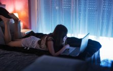 Teenager Mädchen in Nachtwäsche mit Laptop auf Bett im Zimmer — Stockfoto
