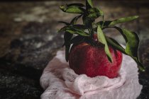 Сырое красное яблоко с листьями на темном потрепанном столе — стоковое фото