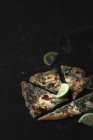 Tranches de citron vert frais et morceaux de délicieux gozleme sur une table sombre — Photo de stock