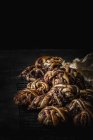 Heap of delicious chocolate buns on metal grating on dark background — Stock Photo
