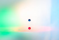 Gros plan de éclaboussures de liquide transparent coloré sur fond coloré — Photo de stock