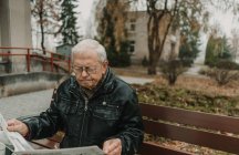 Літній чоловік читає газету в парку — стокове фото