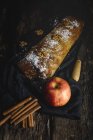 Домашний яблочный штрудель с орехами, изюмом и корицей на фоне темного дерева — стоковое фото