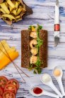 De cima vista de legumes fatiados e queijo com sanduíche grande colocado no meio sobre fundo de madeira — Fotografia de Stock