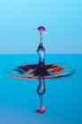 Primo piano di spruzzi di liquido trasparente di colore su sfondo blu — Foto stock
