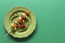 Makkaroni mit Tomate und Basilikum am Stiel auf grünem Hintergrund — Stockfoto