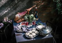 Tablecloth setting with artichokes, red wine and jam serrano leg. — Stock Photo