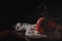 Сырое красное яблоко с листьями на темном столе — стоковое фото