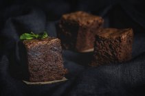 Кусочки шоколадного брауни с мятой на черной ткани — стоковое фото