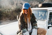 Junge Frau in Freizeitkleidung sitzt auf Auto — Stockfoto