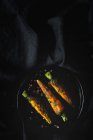 Gesunde geröstete Karotten mit Kräutern und Gewürzen auf schwarzem Stoff — Stockfoto