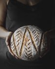 Closeup of female hands holding loaf of fresh bread — Stock Photo