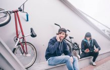 Young men poses with mobile and BMX bicycle. — Stock Photo