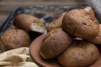Petits pains frais cuits au four en tas sur une assiette brune — Photo de stock