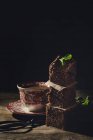 Pezzi impilati di brownie al cioccolato con menta su sfondo scuro con tazza di caffè — Foto stock