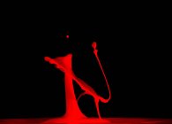 Nahaufnahme von Spritzer roter Flüssigkeit auf schwarzem Hintergrund — Stockfoto