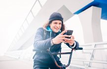 Young man poses with mobile and BMX bike. — Stock Photo