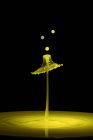 Closeup shot of splash of yellow liquid of color on black background — Stock Photo