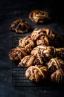 Tas de délicieux petits pains au chocolat sur grille métallique sur fond sombre — Photo de stock