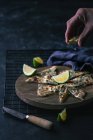 Mão de pessoa anônima espremendo limão fresco em fatias de gozleme na tábua de madeira — Fotografia de Stock