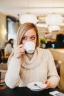 Jovem mulher encantadora segurando copo no café — Fotografia de Stock