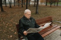 Homme âgé lisant un journal dans le parc — Photo de stock