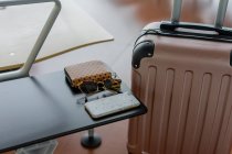 Pink suitcase near table with sunglasses and smartphone — Stock Photo