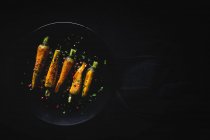Gesunde geröstete Karotten mit Kräutern und Gewürzen auf dunklem Hintergrund — Stockfoto
