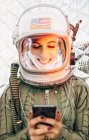 Жіночий астронавт в освітленому вінтажному шоломі з мобільним телефоном — стокове фото