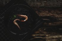 Massa preta com camarão servido em placa preta na mesa de madeira — Fotografia de Stock