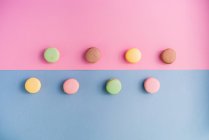From above collection of bright delicious macarons on pink and blue background — Stock Photo