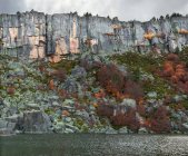 Picturesque view of amazing autumn trees growing on rough cliff near calm water in Soria, Spain — Stock Photo