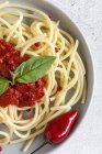 Spaghetti mit Tomatensauce und Basilikum in Schüssel auf weißem Hintergrund — Stockfoto