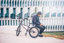 Junger Mann posiert mit Handy und BMX-Rad. — Stockfoto
