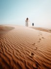 Vista posteriore del turista in piedi al faro in dune sabbiose — Foto stock