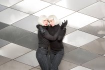 Blond charming ladies in same cloths hugging near wall — Stock Photo