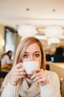 Jovem mulher encantadora segurando copo no café — Fotografia de Stock