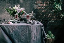 Tablecloth setting with artichokes, flowers and red wine — Stock Photo