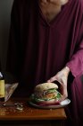 Close-up de mulher desfrutando de cerveja e hambúrguer vegetariano — Fotografia de Stock