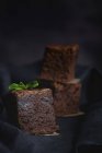 Pieces of chocolate brownie with mint on black fabric — Stock Photo